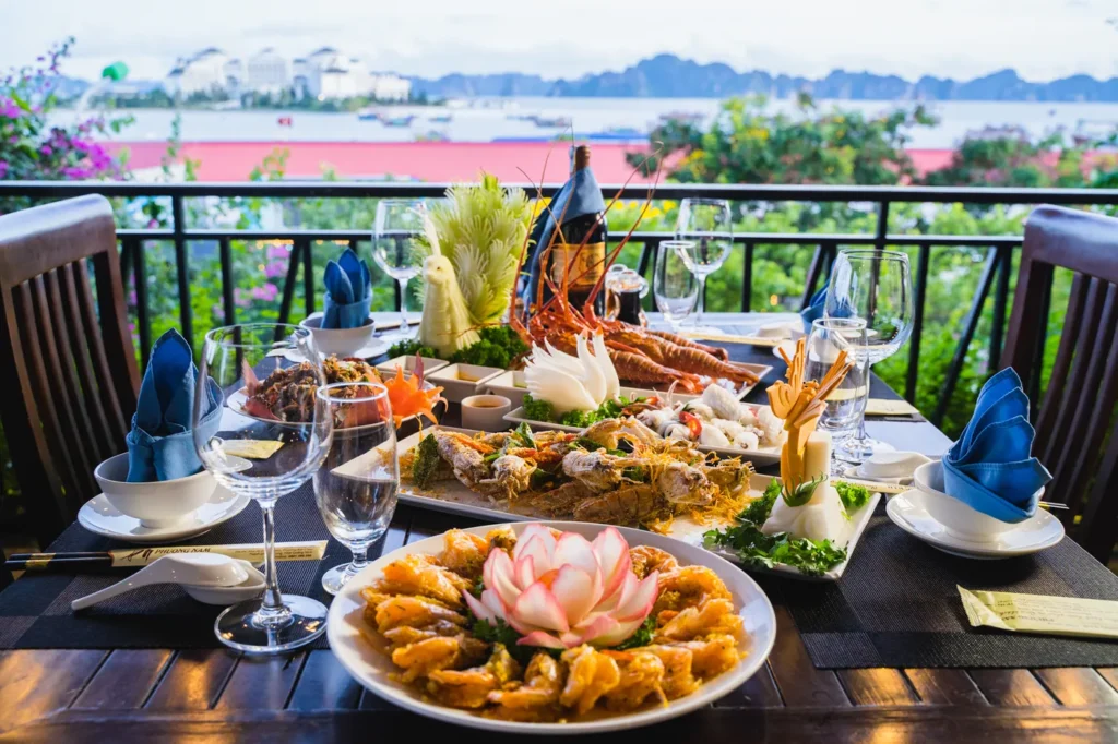 Bàn tiệc hải sản cao cấp với tôm hùm, bề bề và rượu vang trên ban công hướng nhìn ra vịnh Hạ Long và Vinpearl Đảo Rều