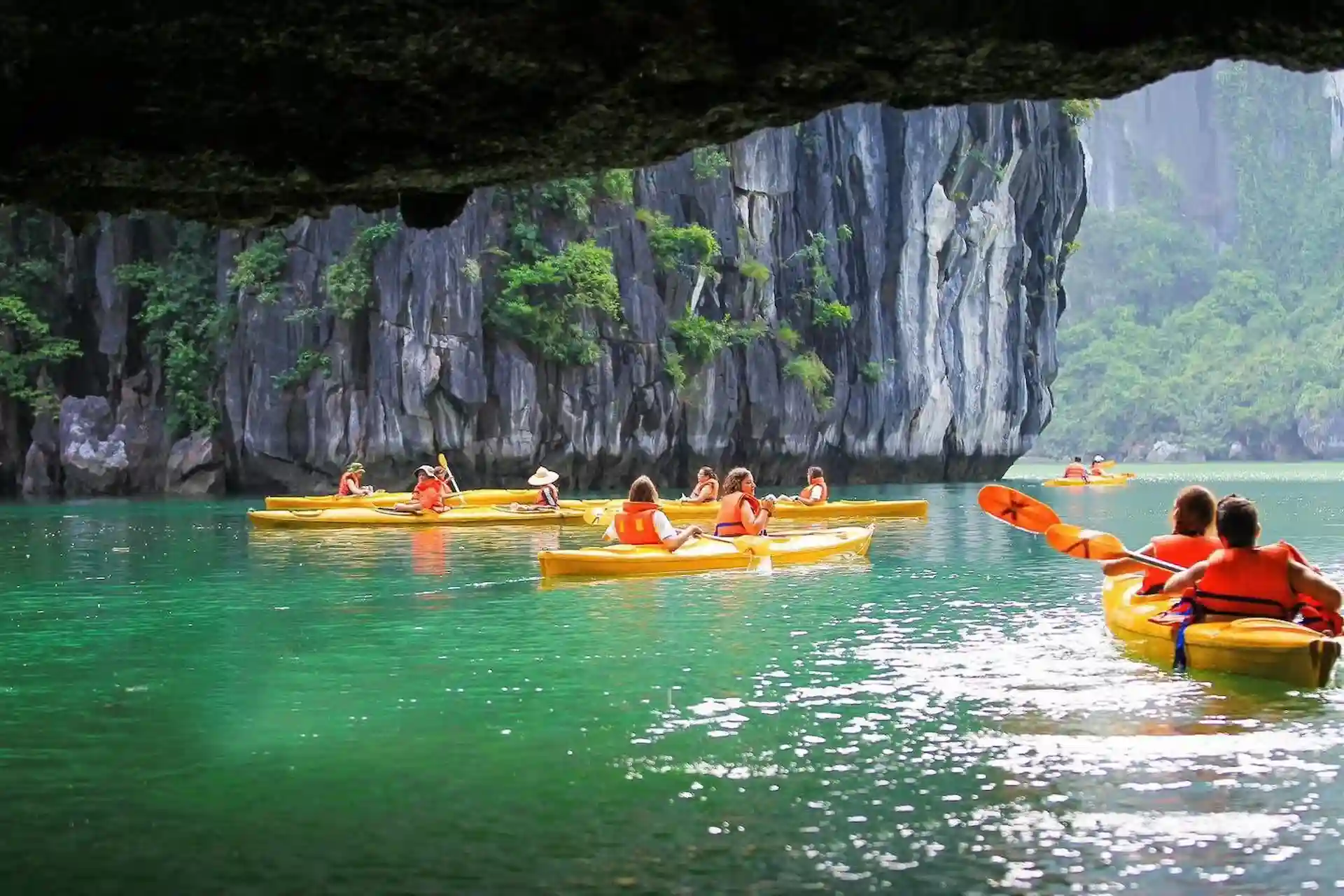 Du khách chèo thuyền kayak khám phá hang động và núi đá vôi trên Vịnh Hạ Long